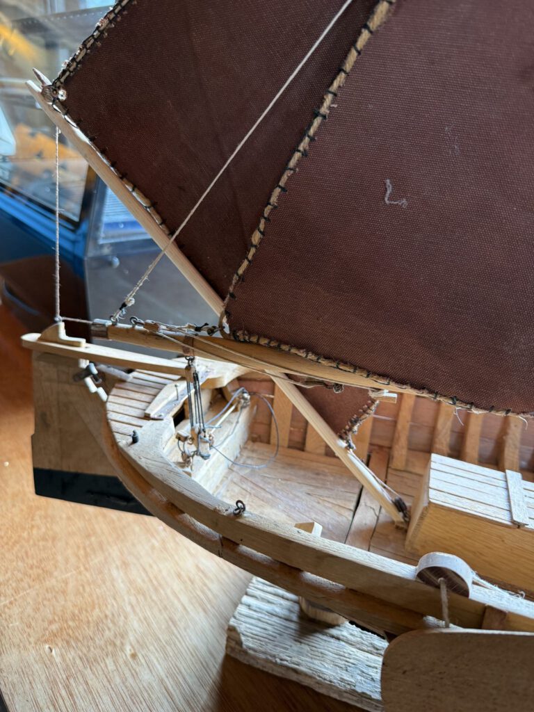 Detail van de handgemaakte tuigage en bruine zeilen van het bottermodel