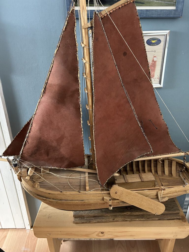 Voorzijde van het houten bottermodel met mast, zeilen en zijzwaarden