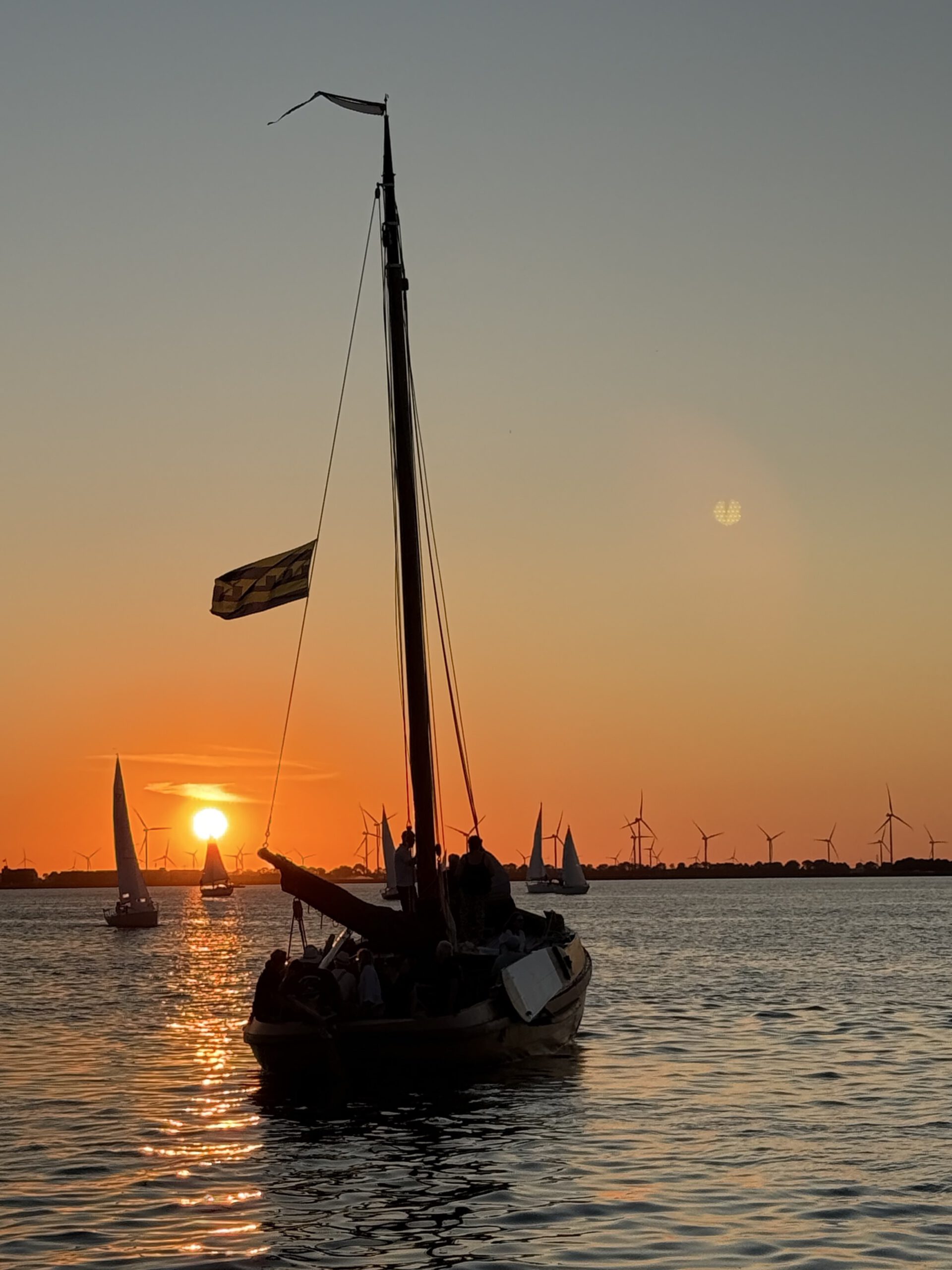 Historische botter tegen de oranje avondlucht op het Wolderwijd